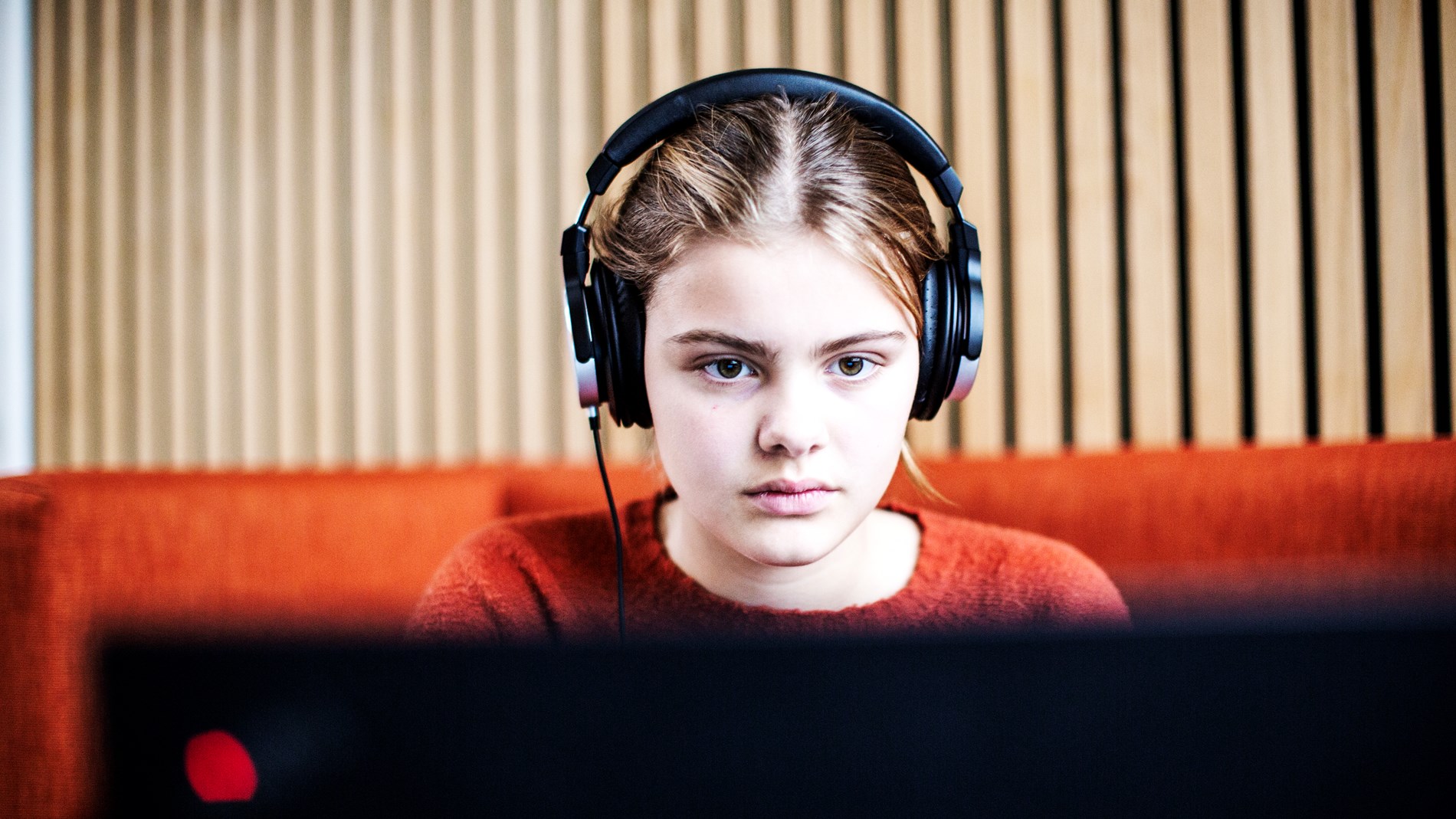 Pige med høretelefoner med en computer